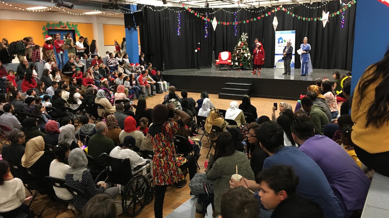 Une foule de nouveaux arrivants est rassemblée dans un gymnase