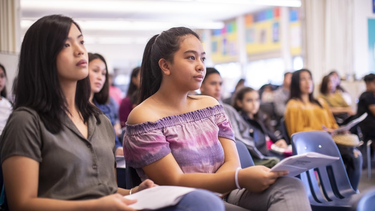 Deux jeunes filles sont asises et écoutent attentivement.