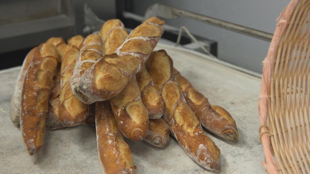 Des baguettes de pain empilées déposées sur une table.