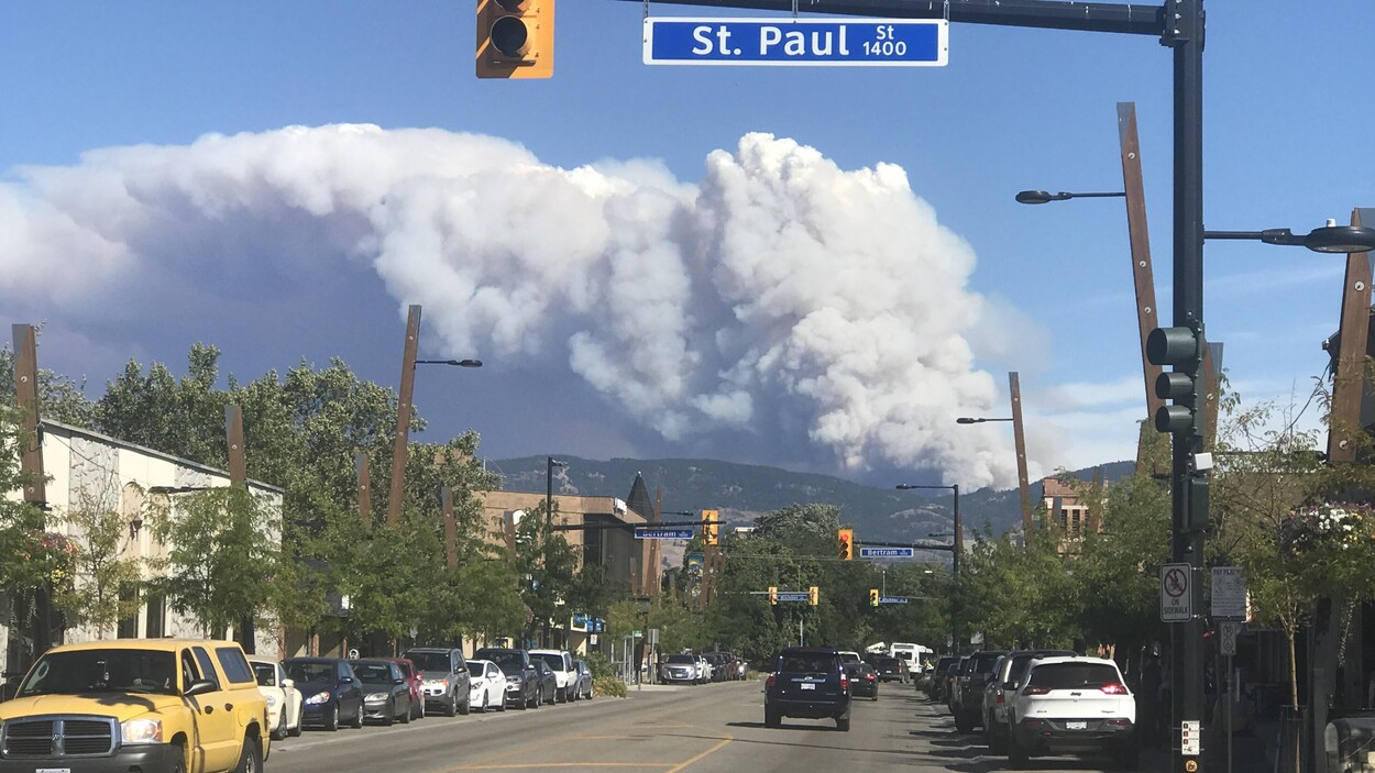 Un panache de fumée s'échappe des montagnes au-dessus d'une rue de Kelowna.