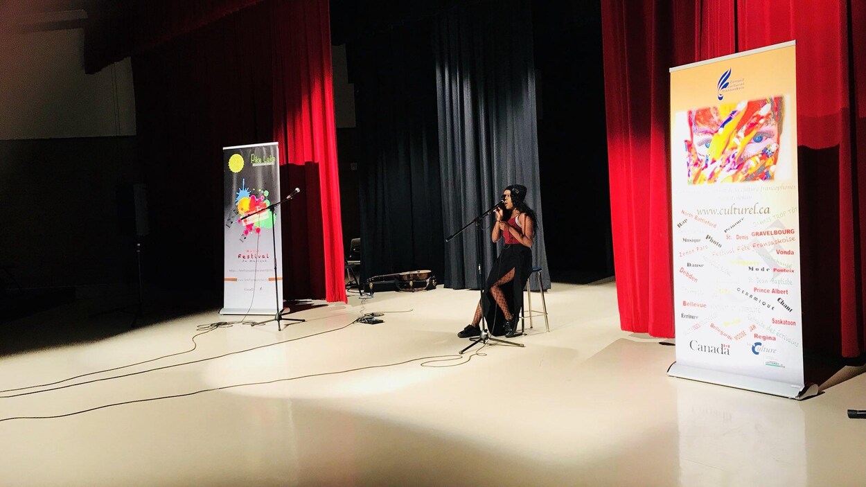 Une jeune femme qui chante assise sur un tabouret