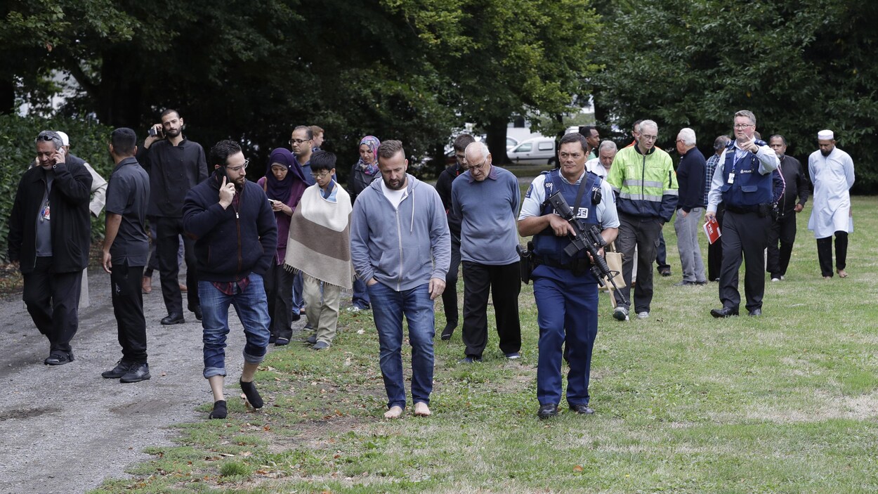 Une foule est escortée par des policiers.