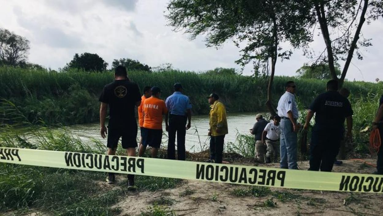 Plusieurs personnes des autorités se tiennent derrière un ruban jaune à proximité du Rio Grande, suite à la noyade d'un migrant salvadorien et de sa fille.