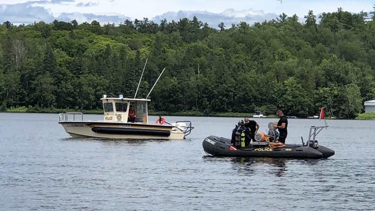 Des plongeurs de la Sûreté du Québec se déplacent dans deux bateaux sur le lac.