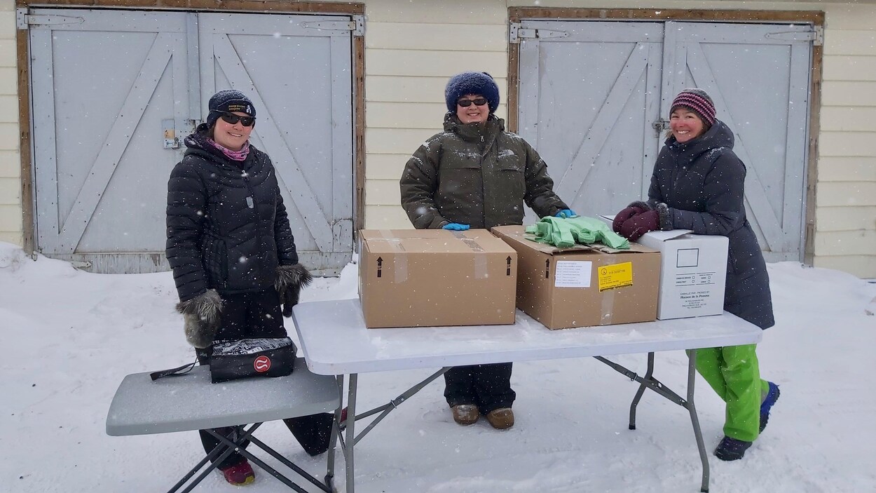 Trois bénévoles attendent devant une table.