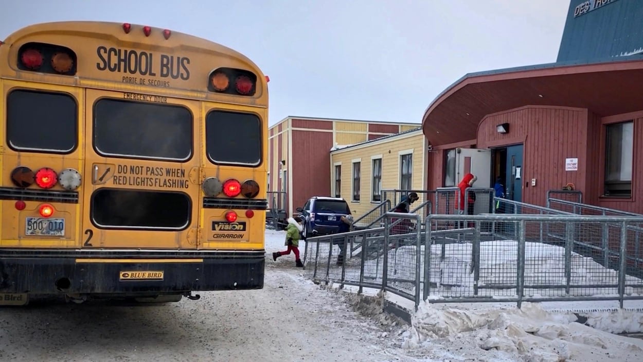Un autobus scolaire dépose des enfants devant une école.
