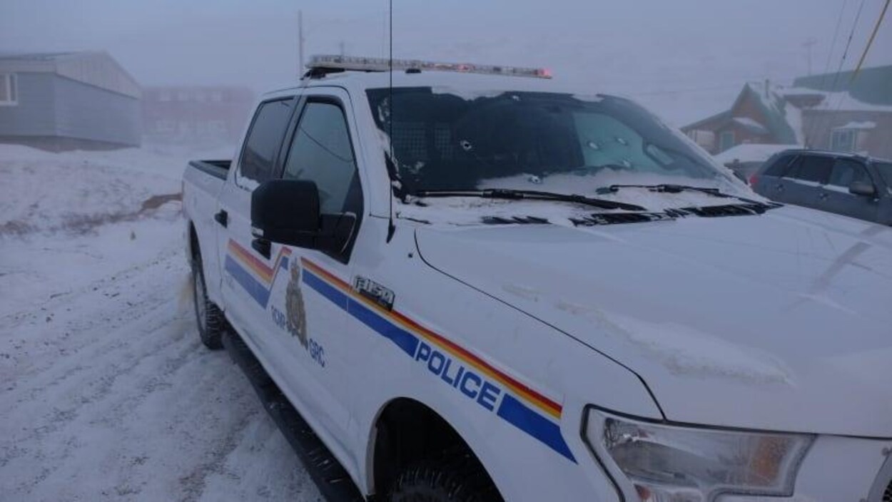 Une camionnette de police sur une rue enneigée.