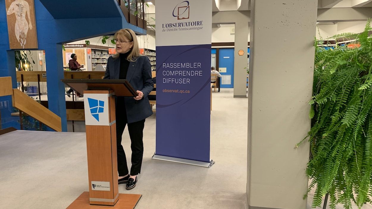 Claire Bolduc parle au lutrin lors d'une conférence de presse dans une bibliothèque.