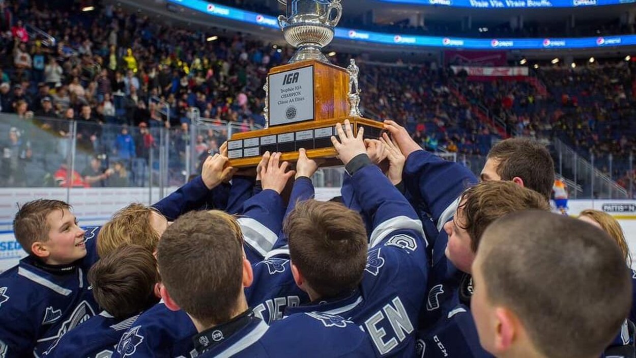 Des jeunes tendent le bras vers un trophée soulevé au-dessus de leurs têtes.