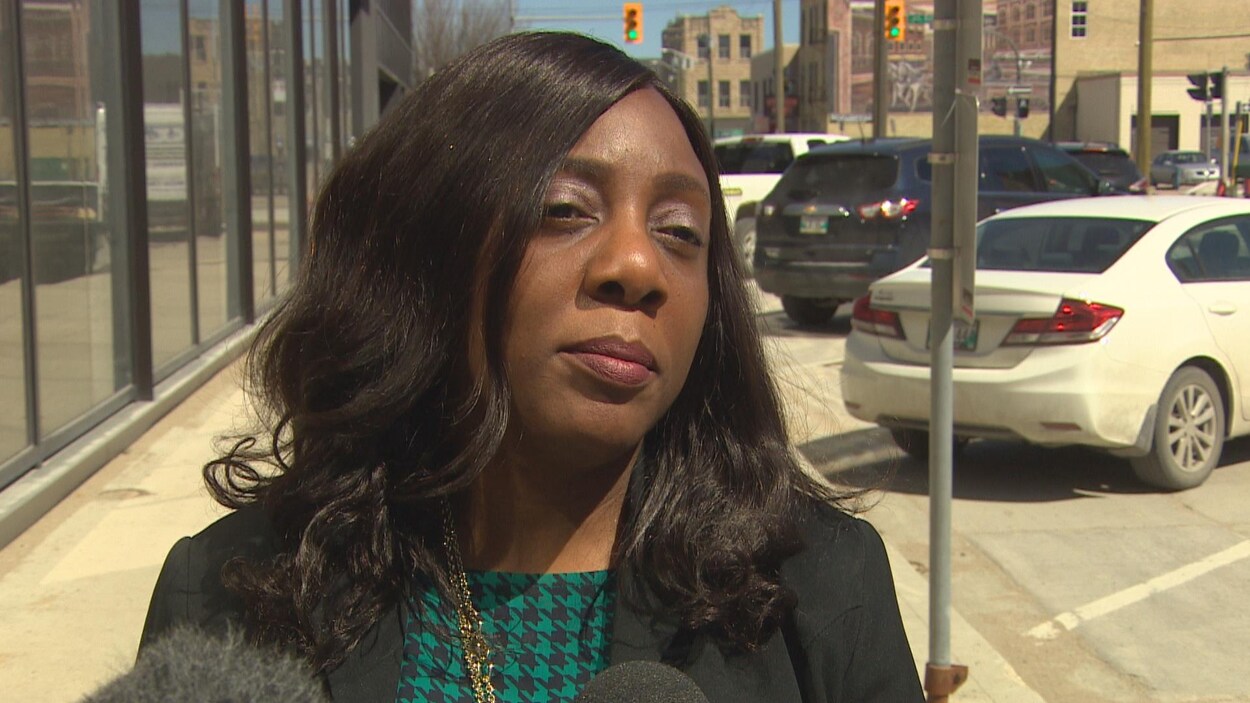 Bunmi Fatoye répond aux questions des journalistes sur un trottoir lors d'une journée ensoleillée.