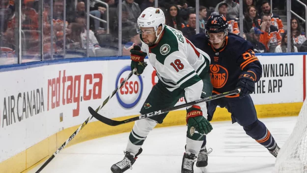 Jordan Greenway et Matt Benning sont sur la glace et luttent pour contrôler la rondelle.