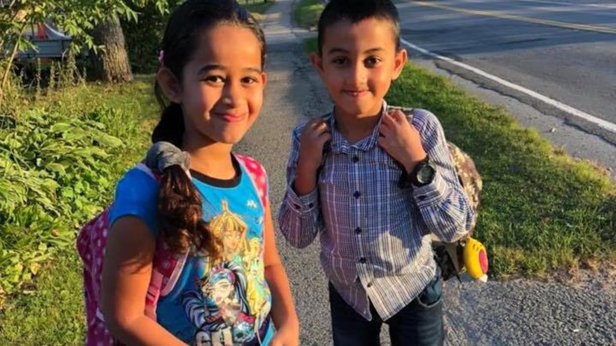 Les deux jeunes enfants de la famille Barho avec un sac à dos, sur le chemin de l'école.