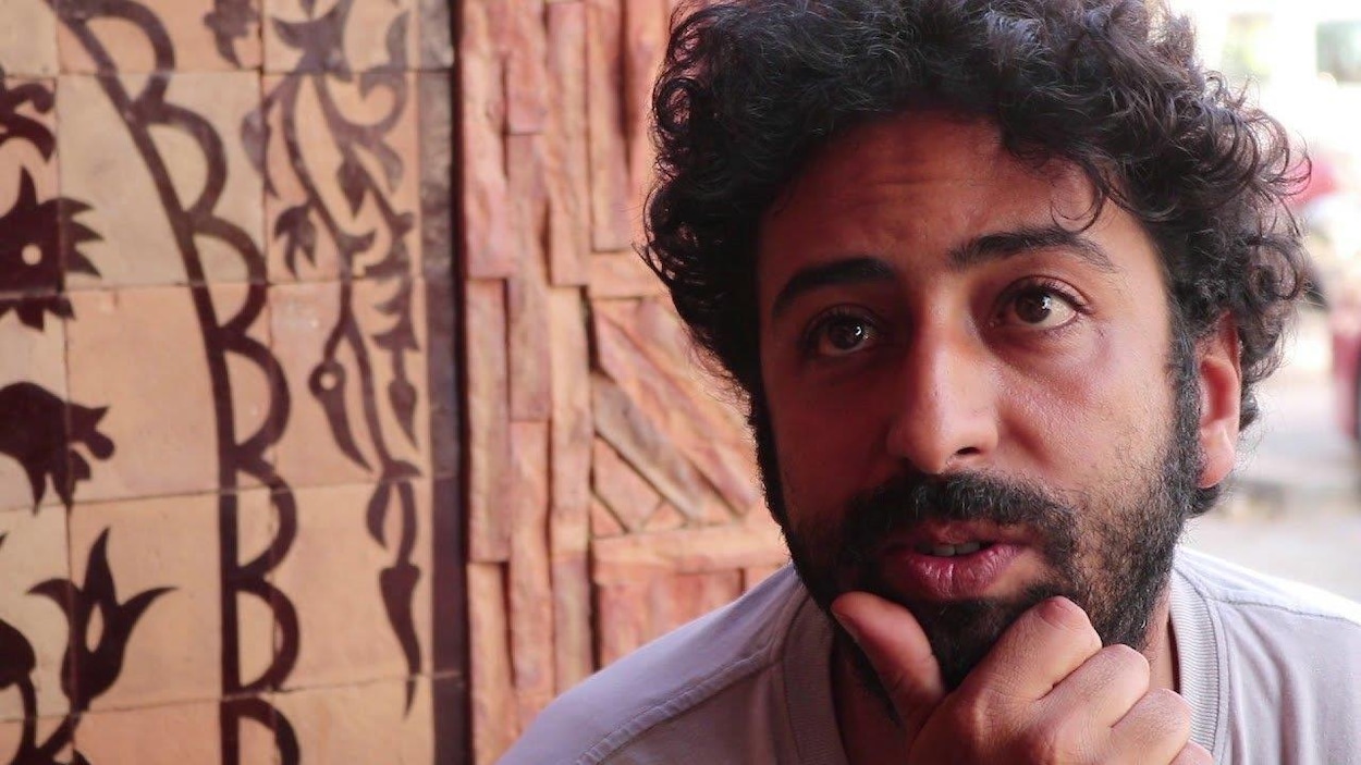 Portrait d'Omar Radi, dans la trentaine, cheveux noirs et bouclés.