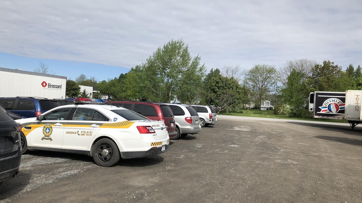 Plusieurs véhicules, dont une voiture de police et un camion d'Olymel, sont stationnés.