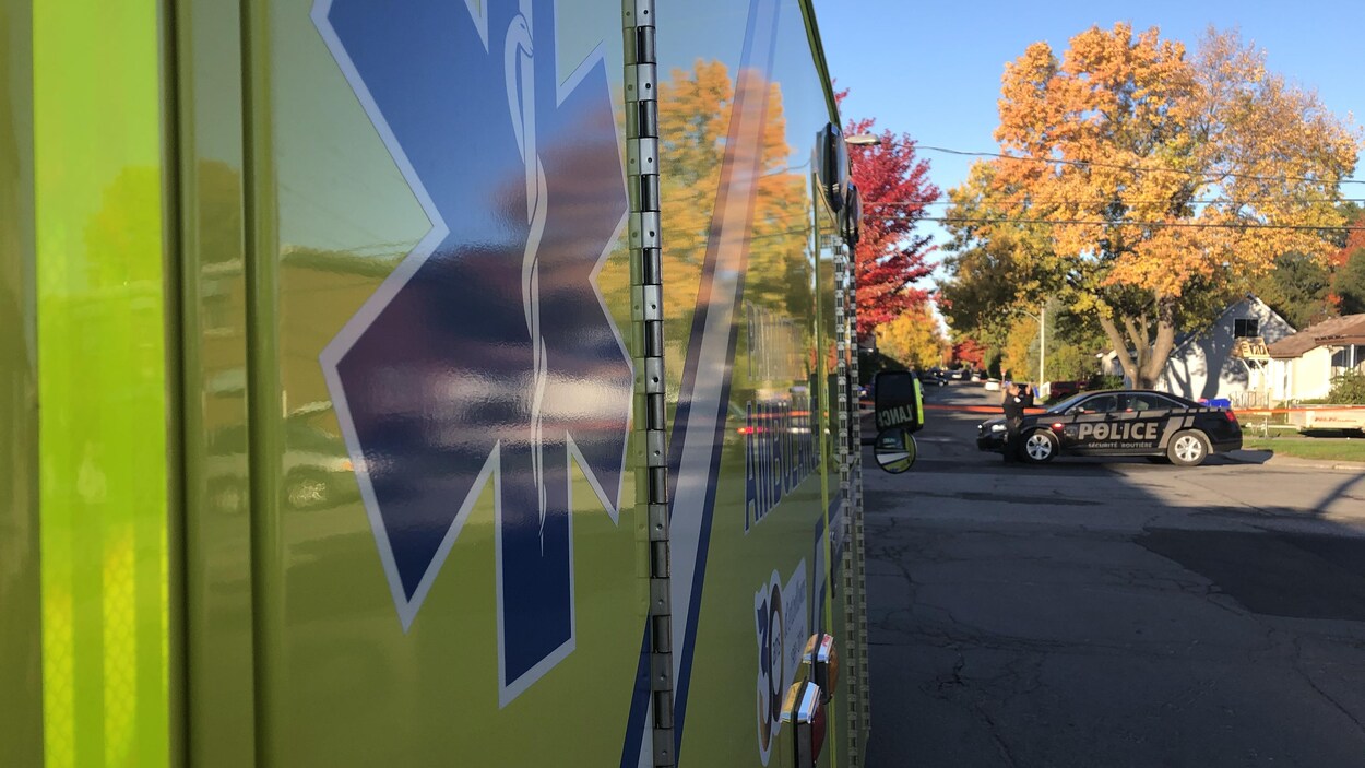 Une ambulance est stationnée dans la rue tandis qu'une autopatrouille est à proximité.