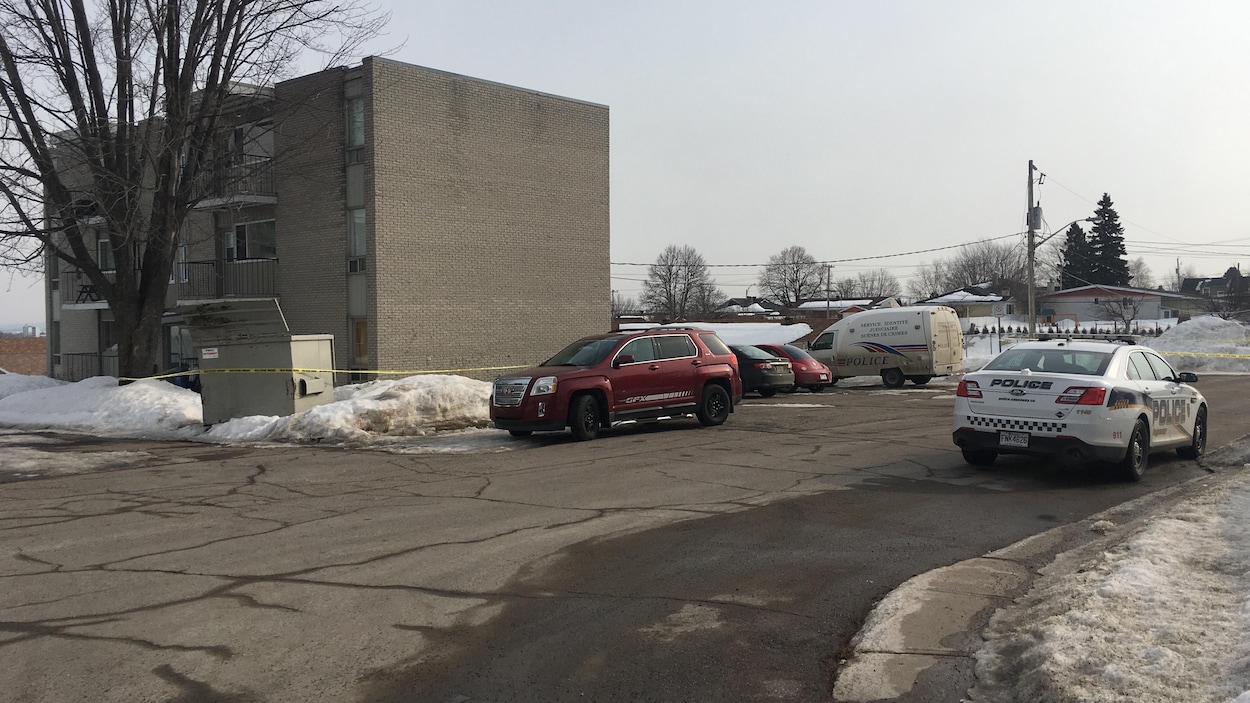Des policiers se trouvent devant un bloc à logement.