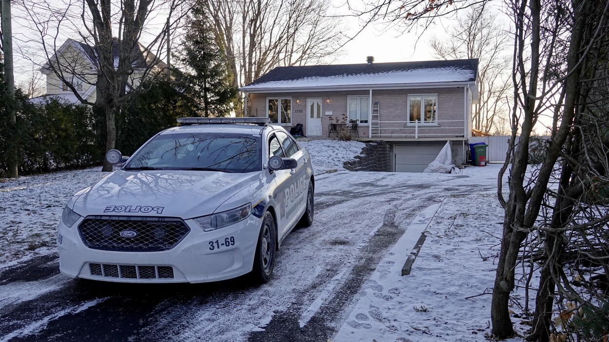 Une voiture de la police de Longueuil stationnée devant une résidence.