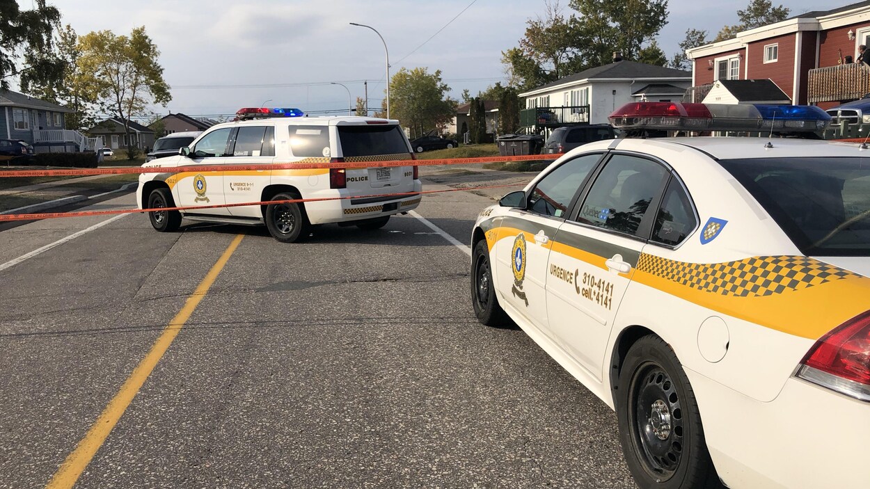 Deux voitures de police et un ruban de sécurité.