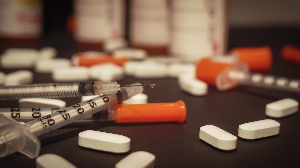 Une seringue usagée et des médicaments éparpillés de façon désordonnée.
