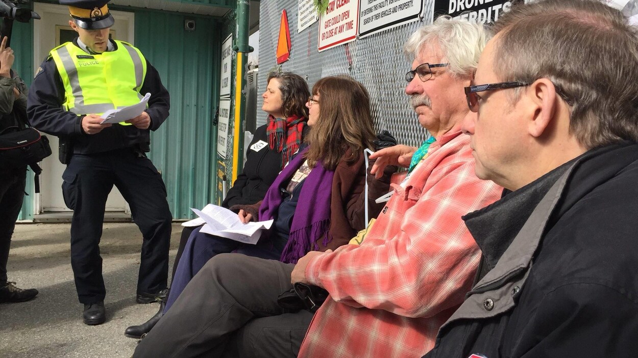 Un agent de la GRC de Burnaby en train de lire l'injonction à des manifestants qui se sont attachés à l'entrée du terminal pétrolier de Kinder Morgan.