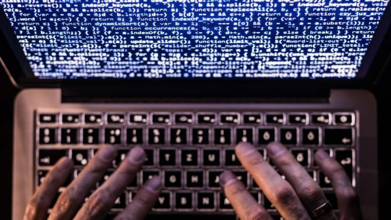 Un homme tape sur un clavier d'ordinateur. 