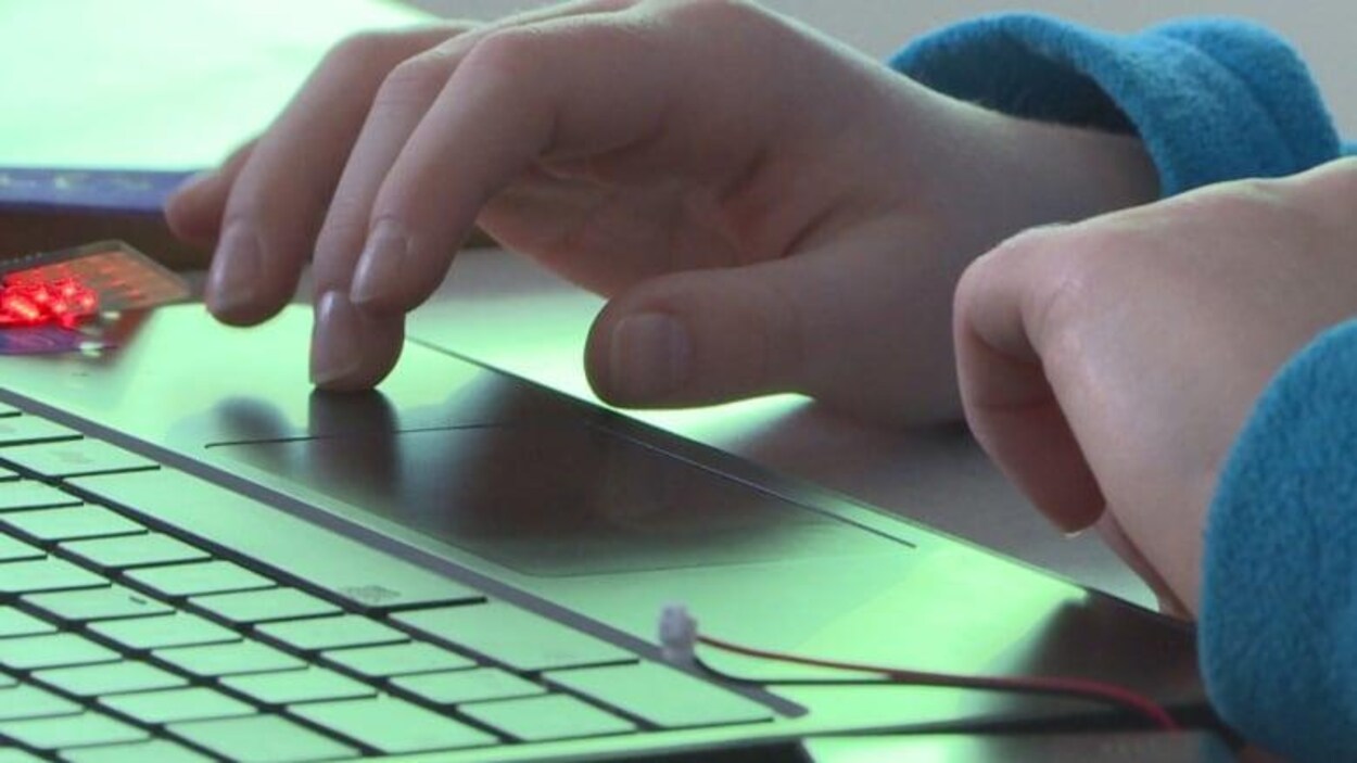 Les mains d'un élève en train de taper sur le clavier d'un ordinateur portable.