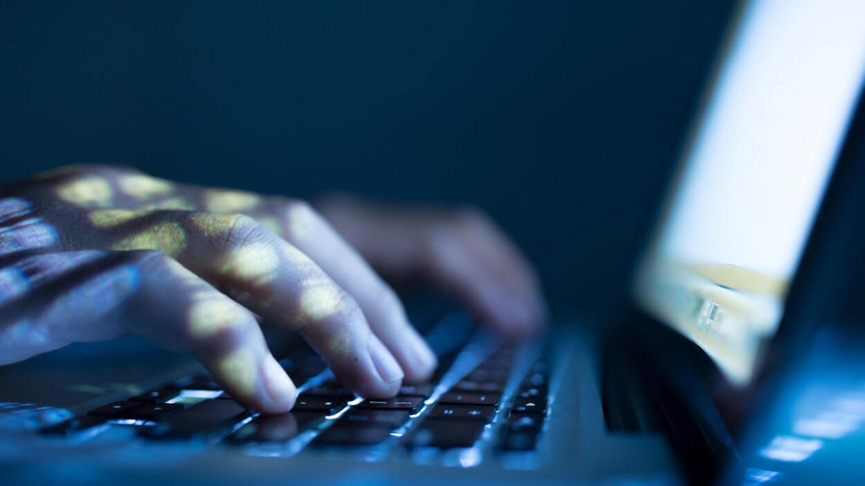 Une personne tape sur un clavier d'ordinateur portable.