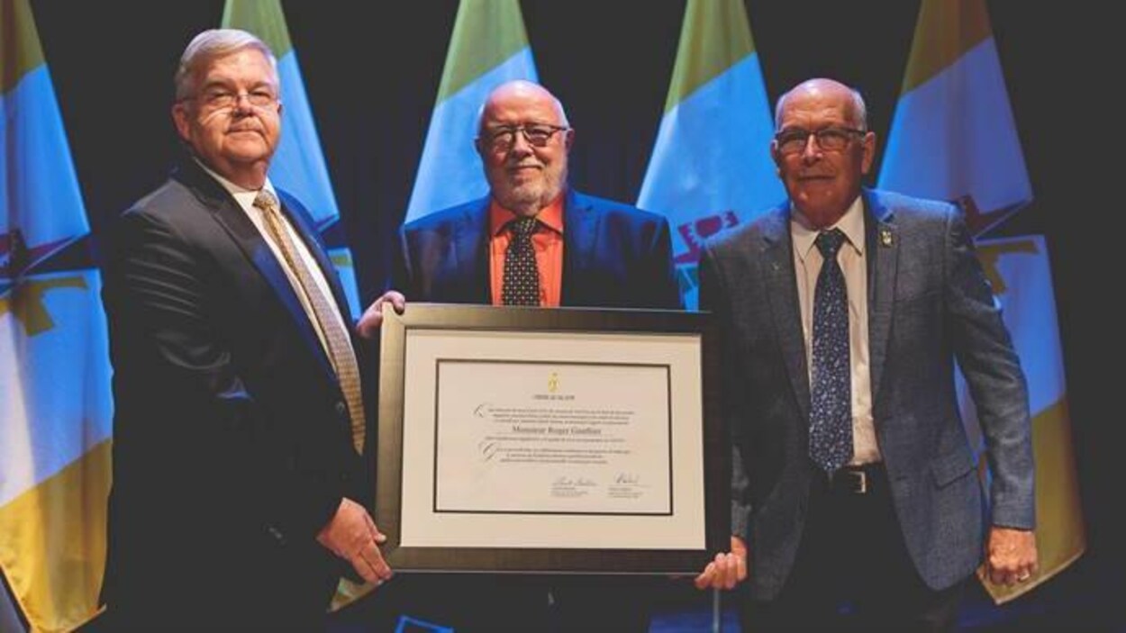 Trois hommes, dont Pierre Corbeil, posent avec un certificat encadré remis à l'Ordre de Val-d'Or.