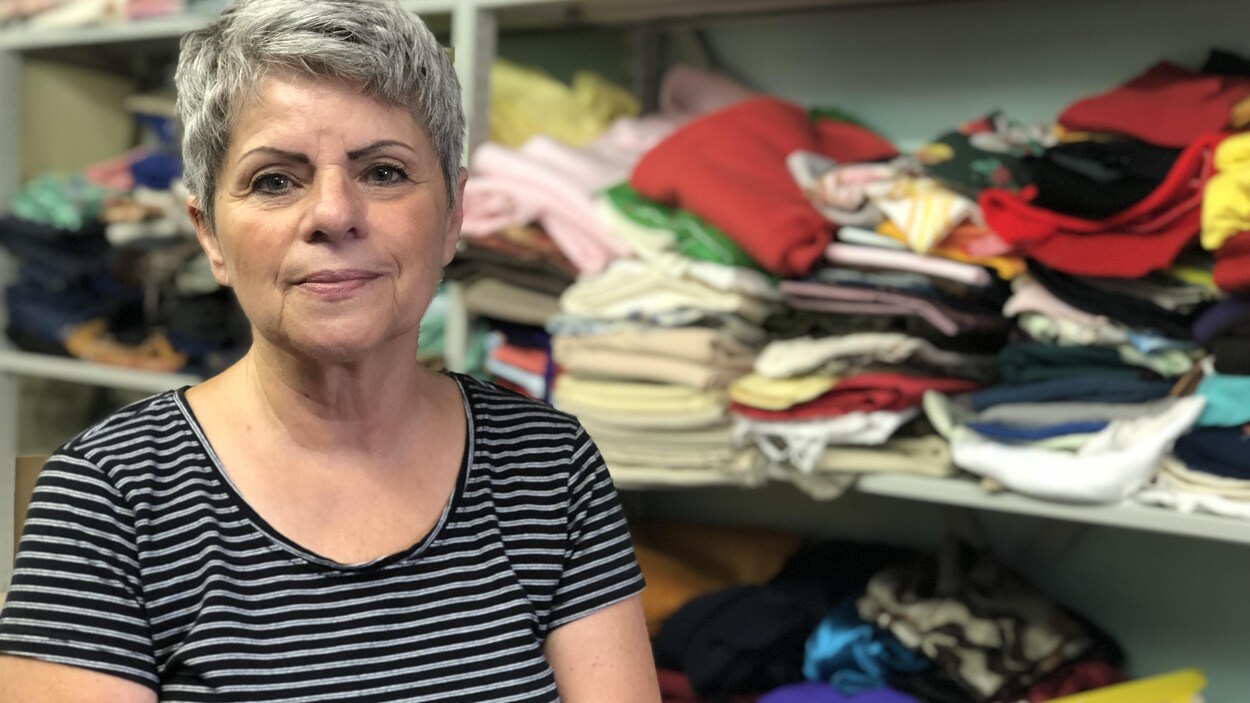 La dame pose d'un plan rapproché devant une tonne de tissus de toutes les couleurs