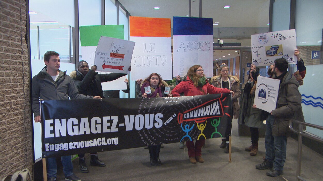 Des membres des organismes communautaires tiennent des pancartes au palais de justice de Gatineau. Des membres des organismes communautaires tiennent des pancartes au palais de justice de Gatineau.