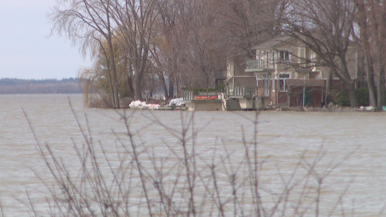 De l'eau se rapproche d'une maison située aux abords de la rivière des Outaouais.