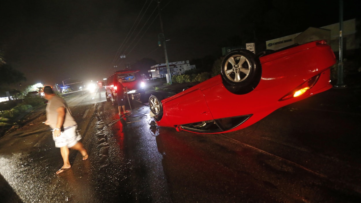 Des gens tentent de redresser un véhicule qui a été renversé sur une route de Cape Coral, pendant l’ouragan Irma, le 10 septembre 2017.