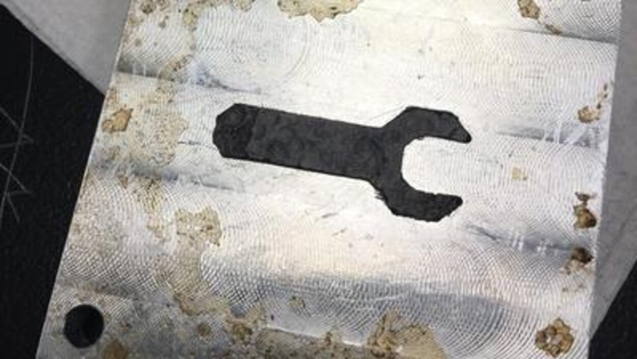 Une clé à molette noire sur une plaque de métal. Une clé à molette noire sur une plaque de métal.