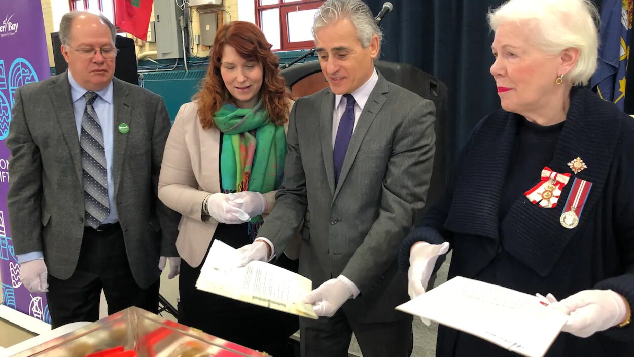 L'archiviste de la Ville, Matt Szybalski, la greffière,Krista Power, le maire de Thunder Bay, Bill Mauro et Elizabeth Dowdeswell regardent le contenu d'une boîte en métal.