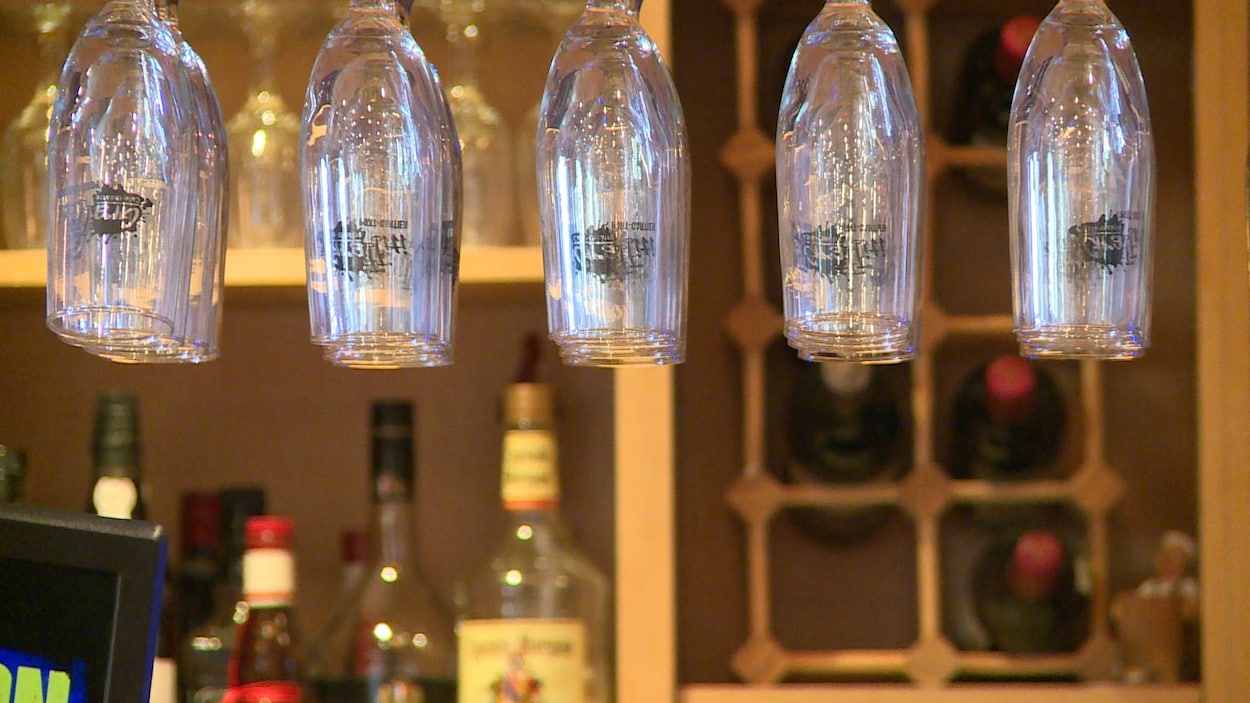 Des verres sont suspendus au-dessus d'un bar dans une salle de spectacle.