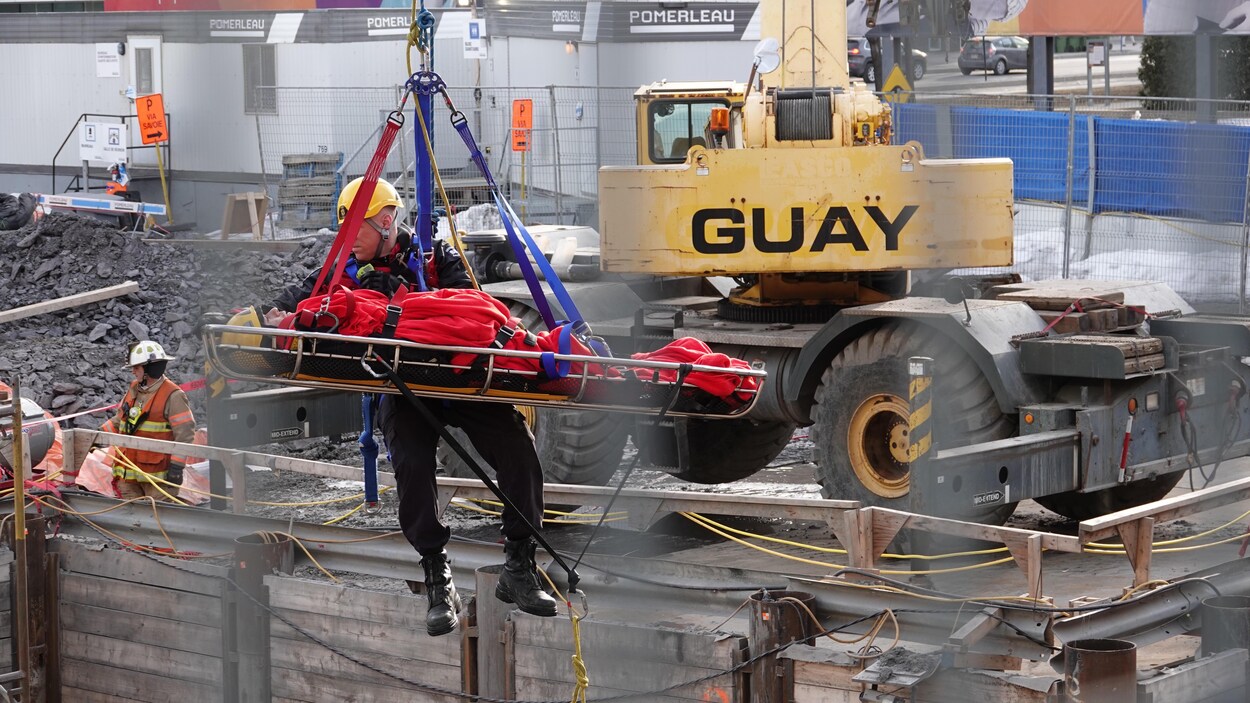 Un pompier sort un homme qui se trouvait au fond d’une tranchée d’excavation à la suite d'un accident de travail survenu sur la rue Berri, à Montréal, le 27 mars 2018.