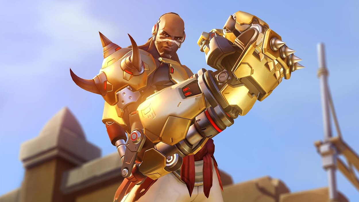 Une capture d'écran du jeu vidéo « Overwatch » montrant un personnage brandissant un énorme poing mécanique devant lui. Une capture d'écran du jeu vidéo « Overwatch » montrant un personnage brandissant un énorme poing mécanique devant lui.
