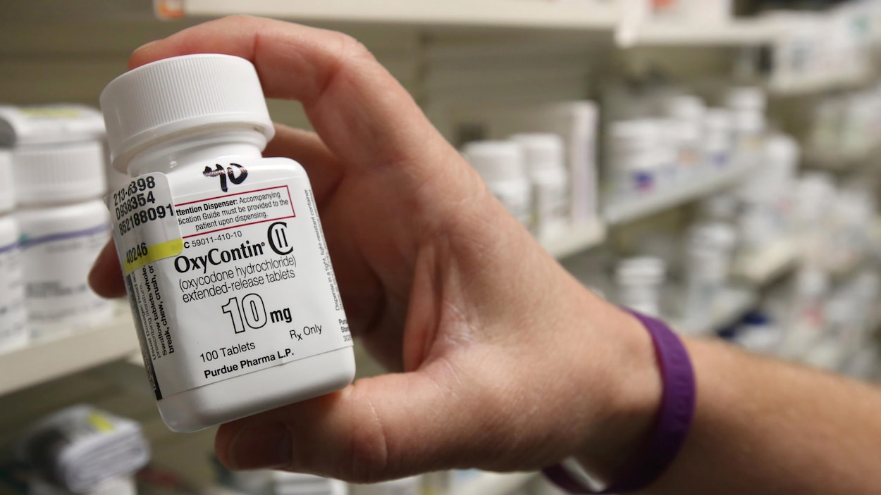 Une bouteille d'OxyContin devant les étagères d'une pharmacie.