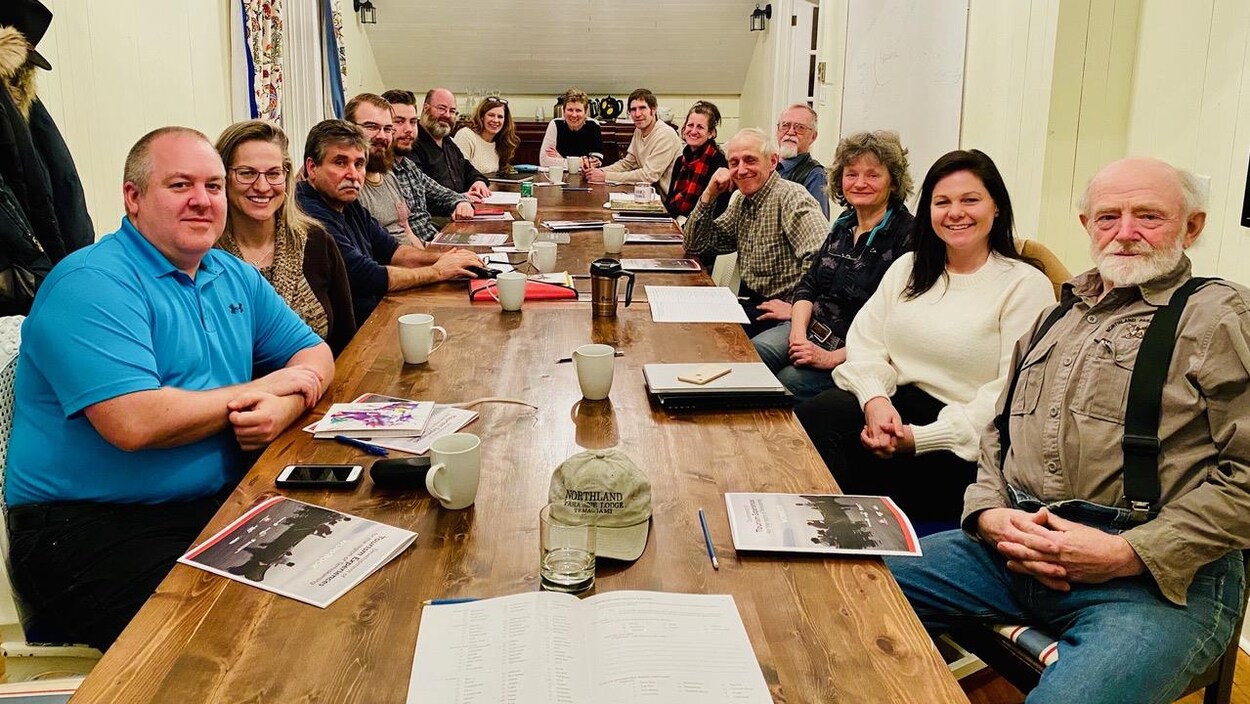 Des personnes réunies autour d'une table avec des tasses de café et des documents d'information.