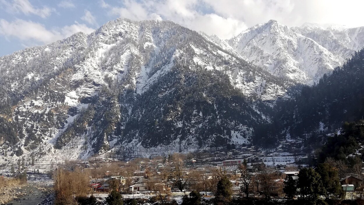 Le village de Kundal Shahi, au pied des montagnes, est couvert de neige.