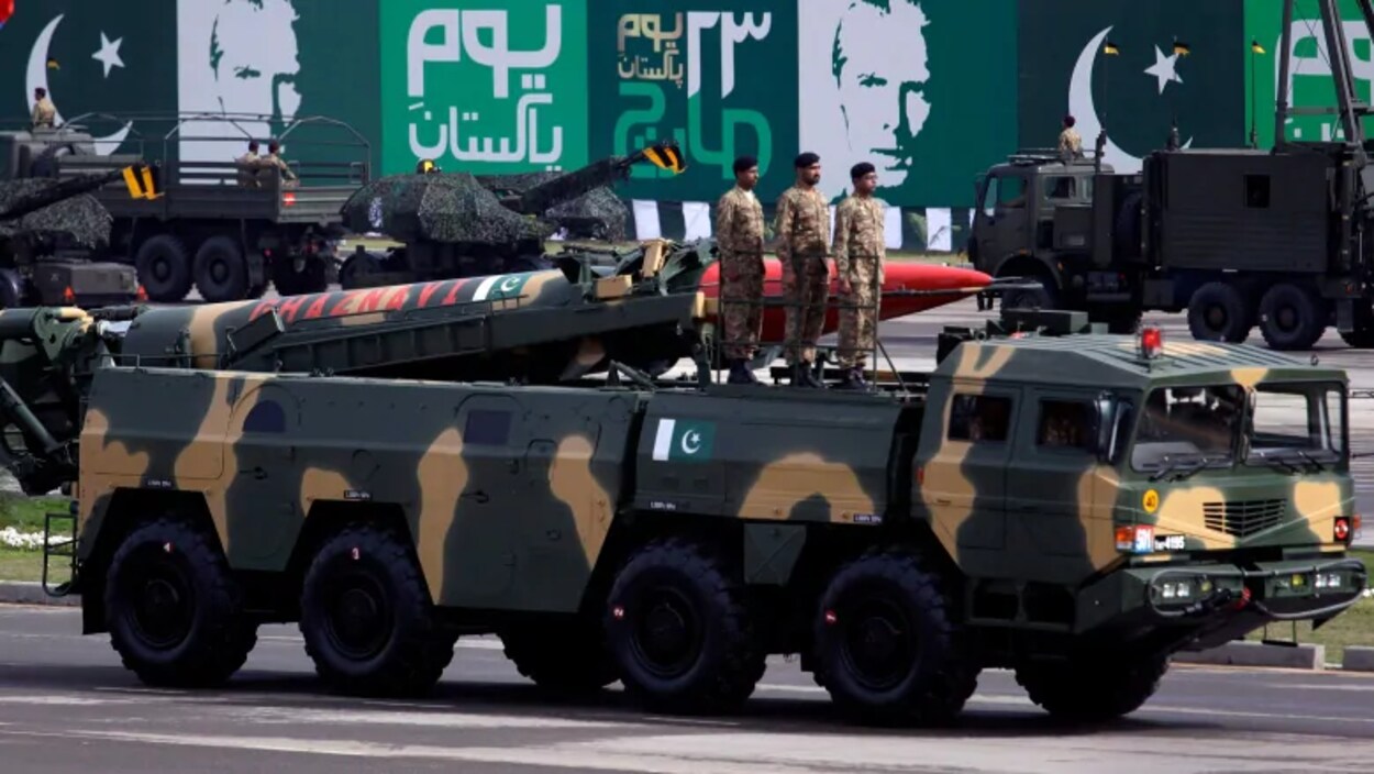 Un camion aux couleurs de camouflage avec des militaires et un missile sur le dessus.