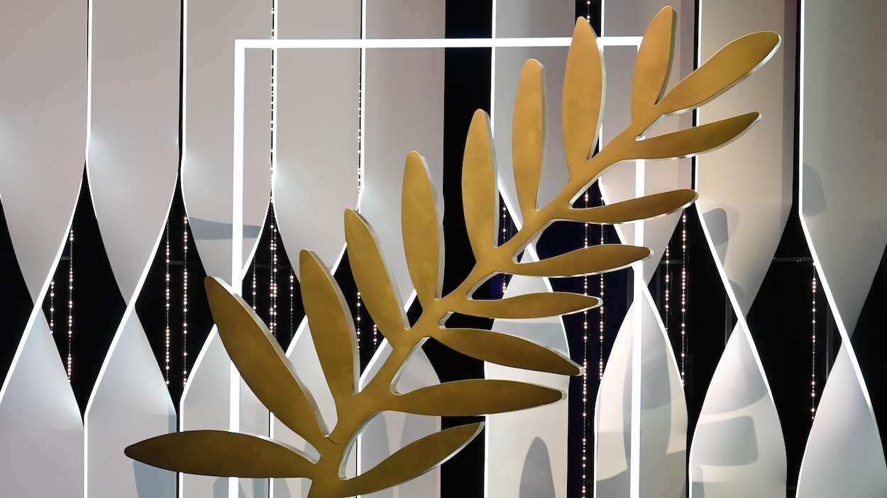 Une sculpture en forme de Palme d'or géante est posée sur une scène éclairée.