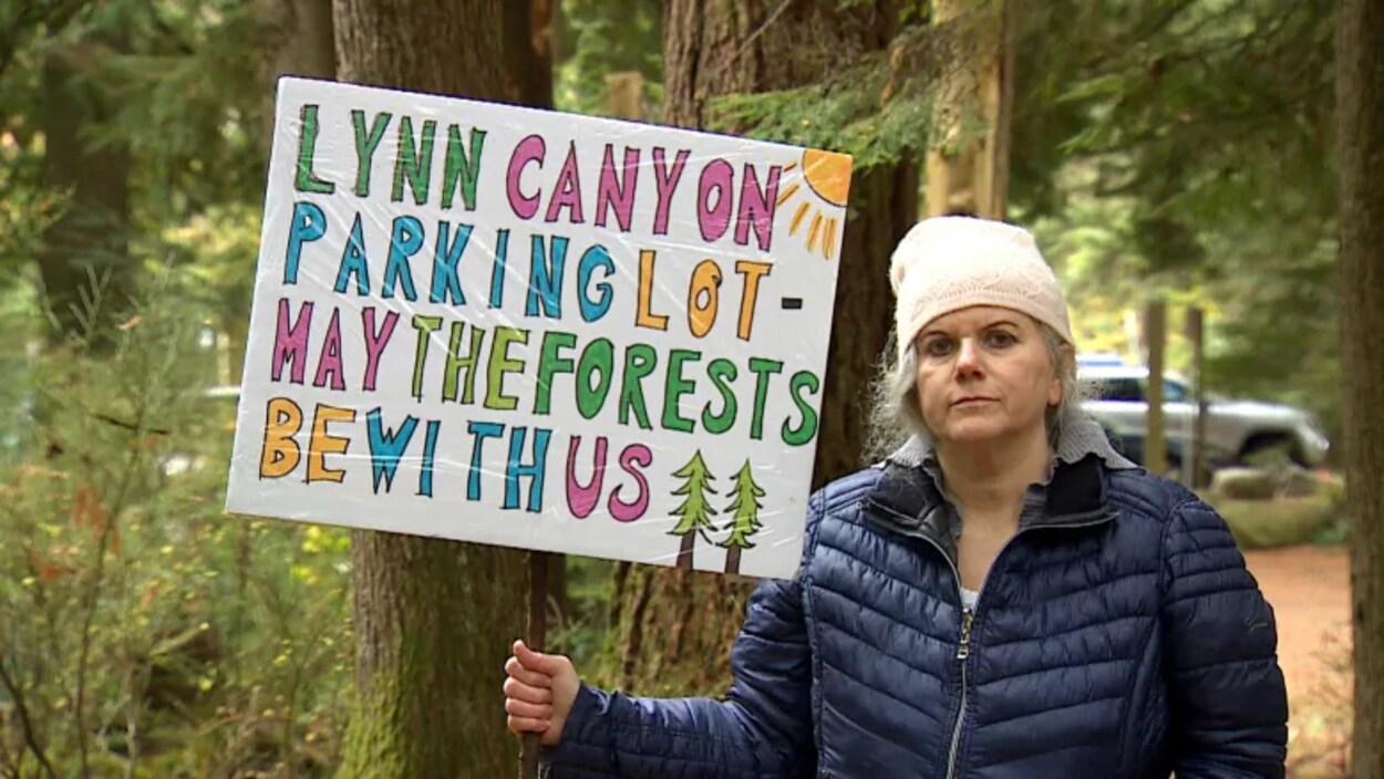 La résidente Kim Hughes tient une pancarte sur laquelle sont écrits les mots : stationnement du canyon Lynn, que la forêt soit avec nous.