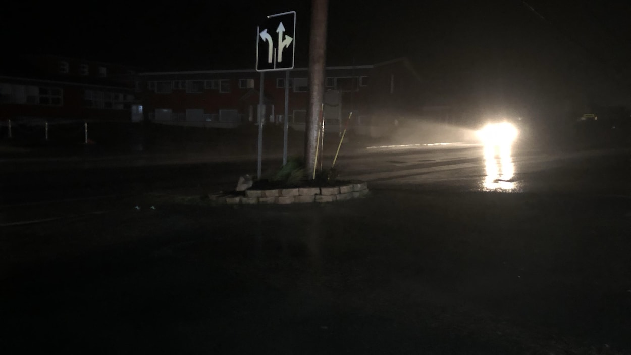 Une automobile circule sur une rue non éclairée.