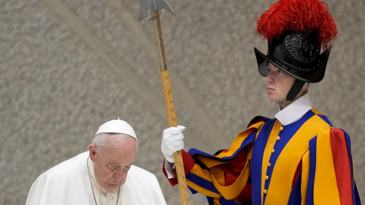 Le pape François passe devant un garde suisse en faction dans la salle Paul VI du Vatican.