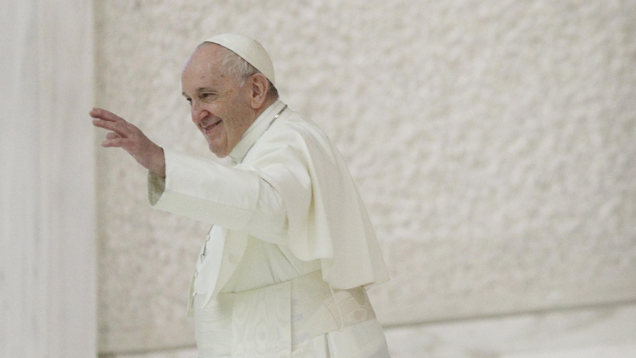 Le pape salue de la main en souriant.