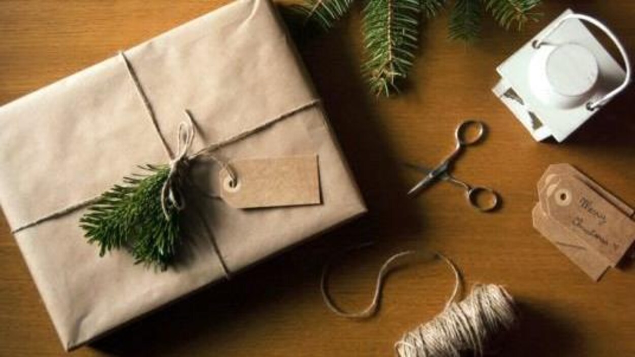 Cadeau emballé dans du papier brun, avec de la ficelle et une branche de sapin.