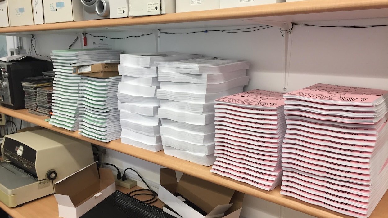 Des piles de feuilles et des cahiers sont empilés sur une tablette.
