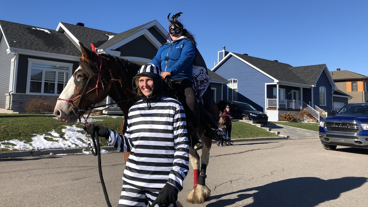 Une femme vêtue d'un costume de prisonnier tire un cheval avec un enfant dessus.