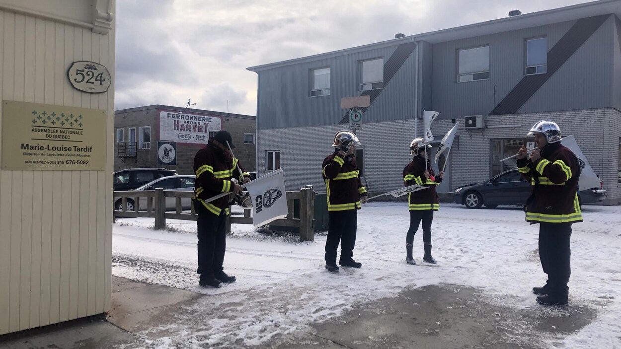 Des ambulanciers manifestent dans une rue enneigée.